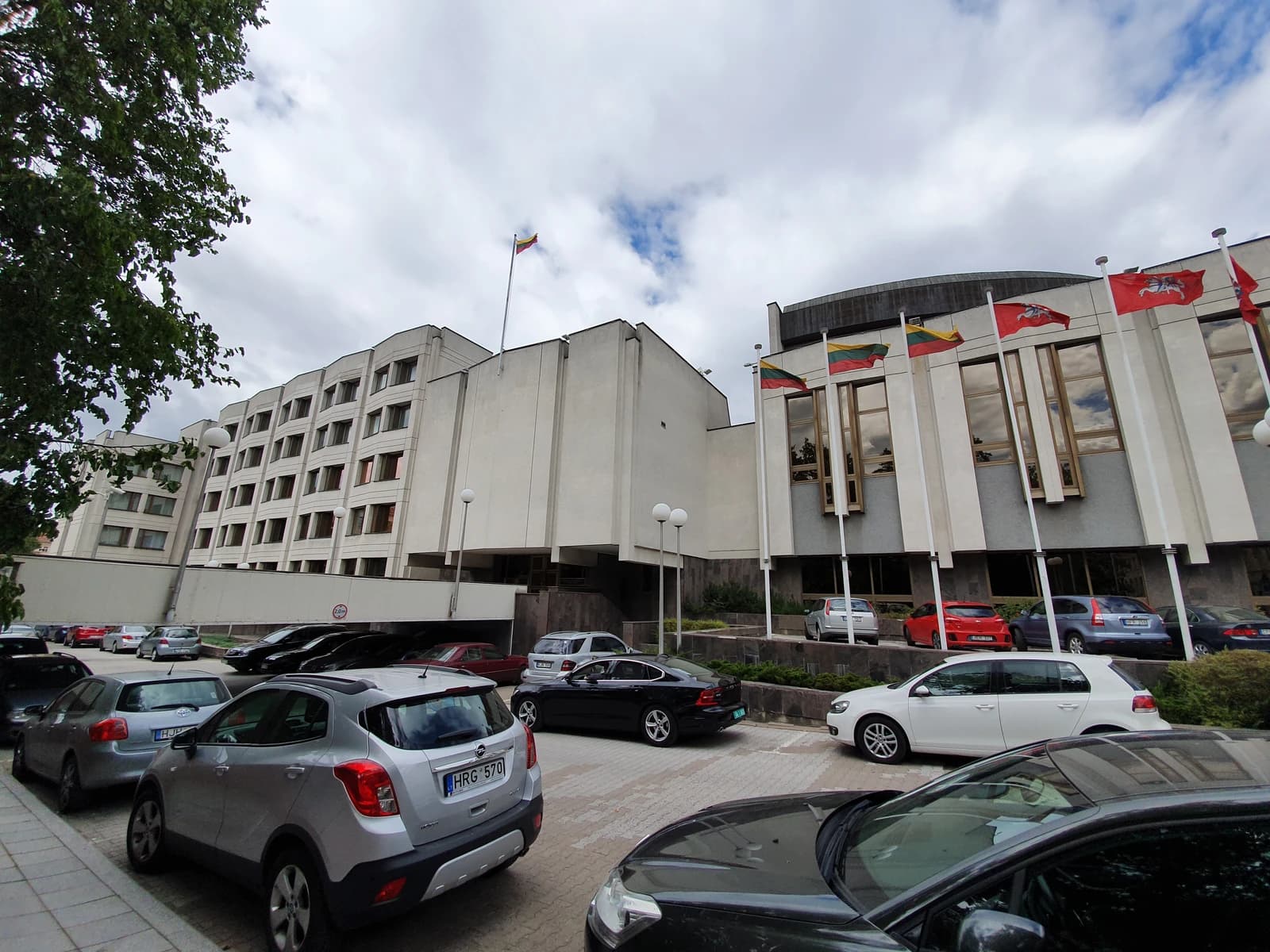 Exterior of the Government of Lithuania building with parked cars and flags.