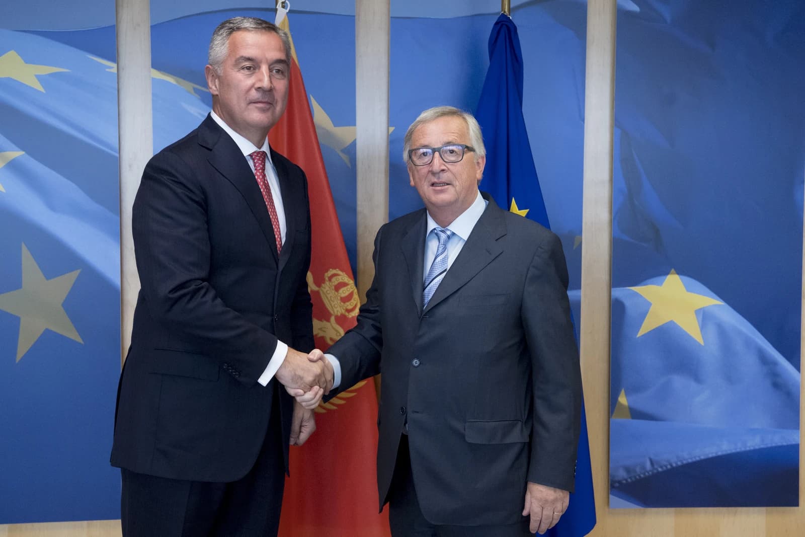 Milo Đukanović and Jean-Claude Juncker shaking hands in front of European Union and Montenegrin flags.
