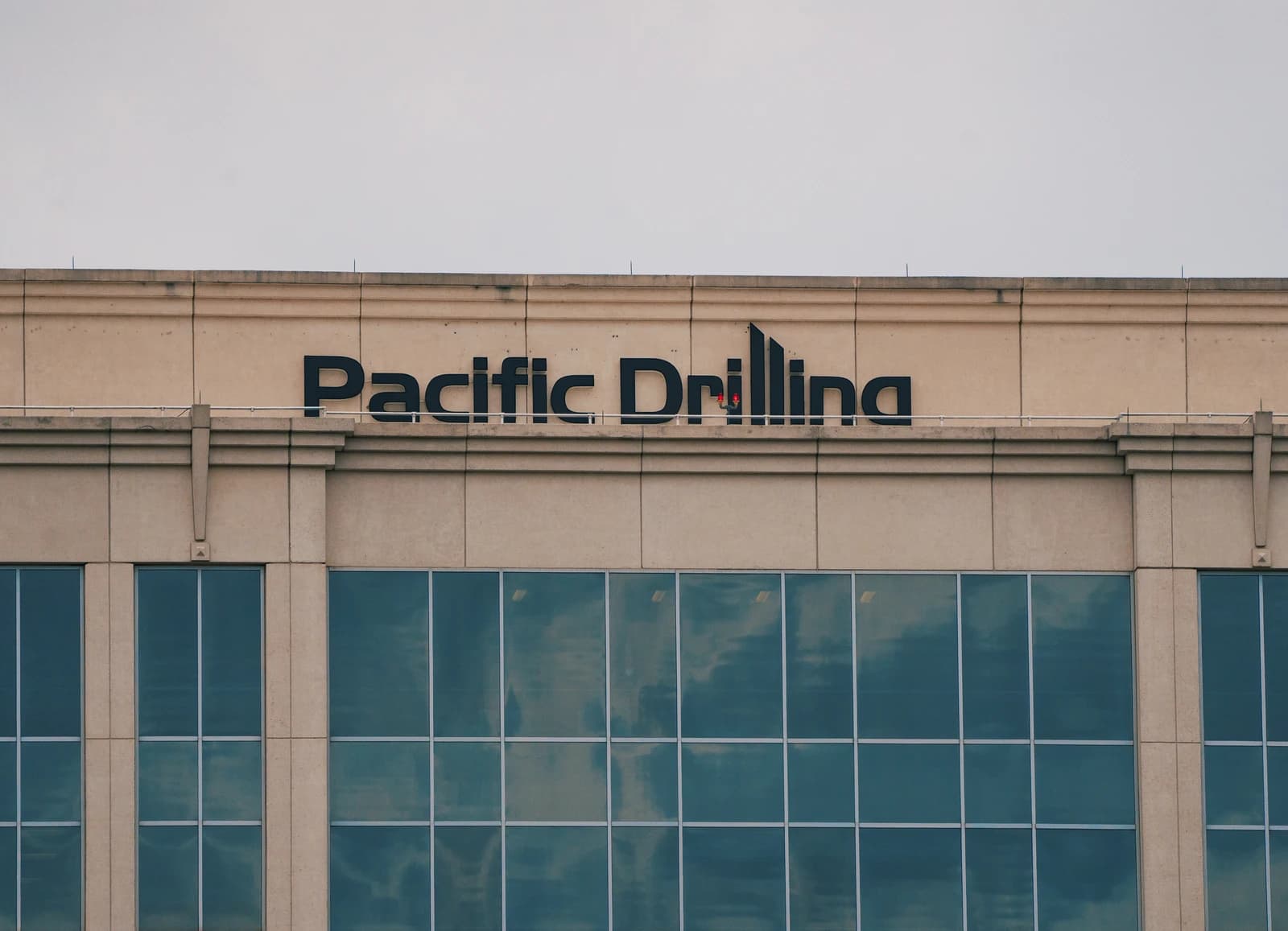 Signage for Pacific Drilling on the side of a building, clear sky above.