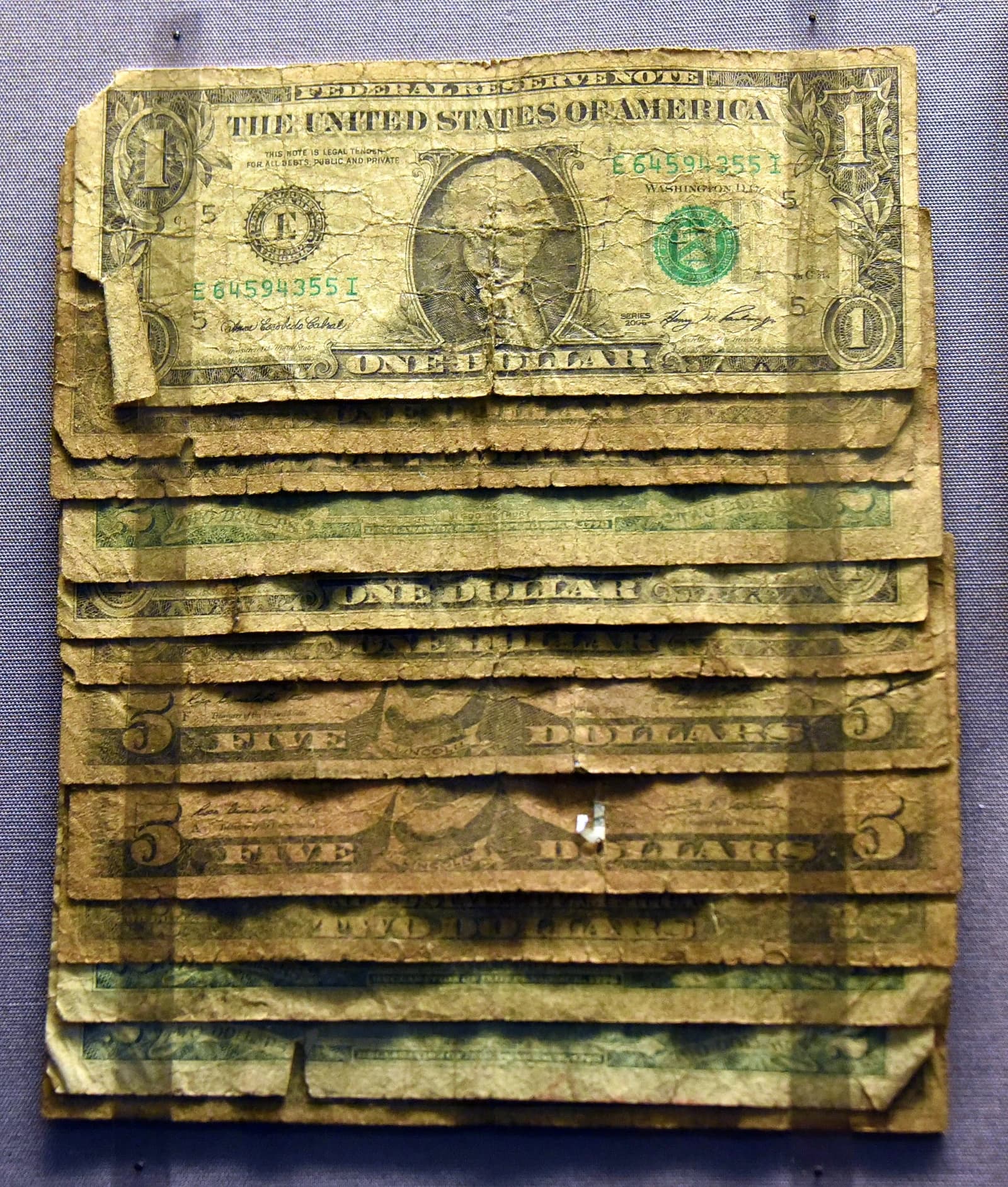 Close-up of old, heavily worn US dollar banknotes on display at a museum.