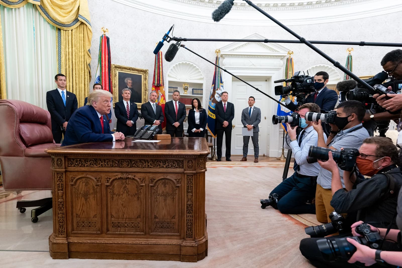 Donald Trump, former President, speaking from behind a large desk to reporters.