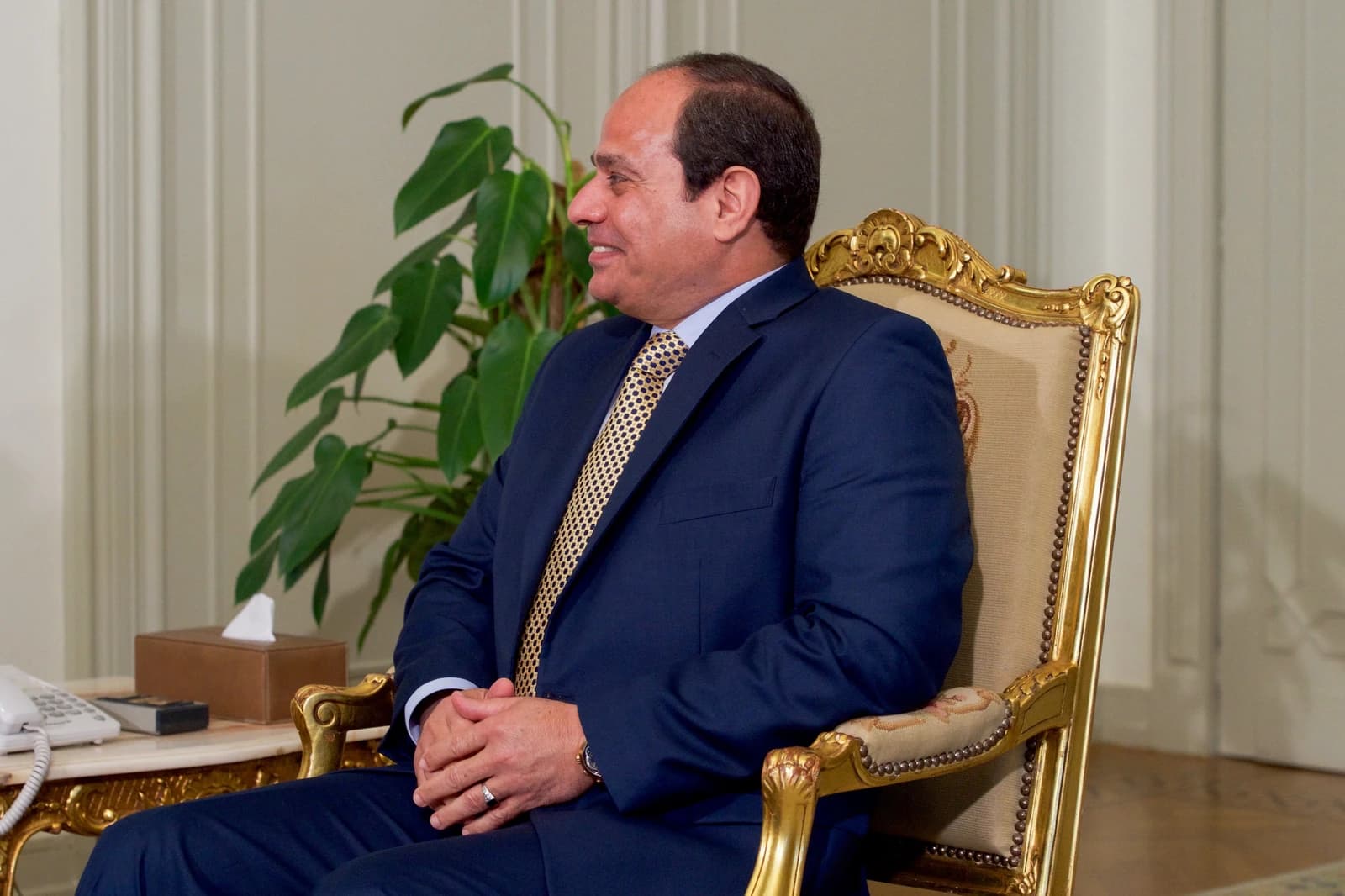 Egyptian President Abdel Fattah el-Sisi sitting in a gold-framed chair.