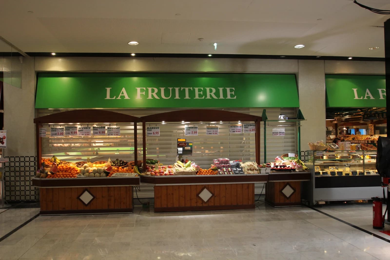 Fruit and vegetable stands display various produce items with visible prices in a store.