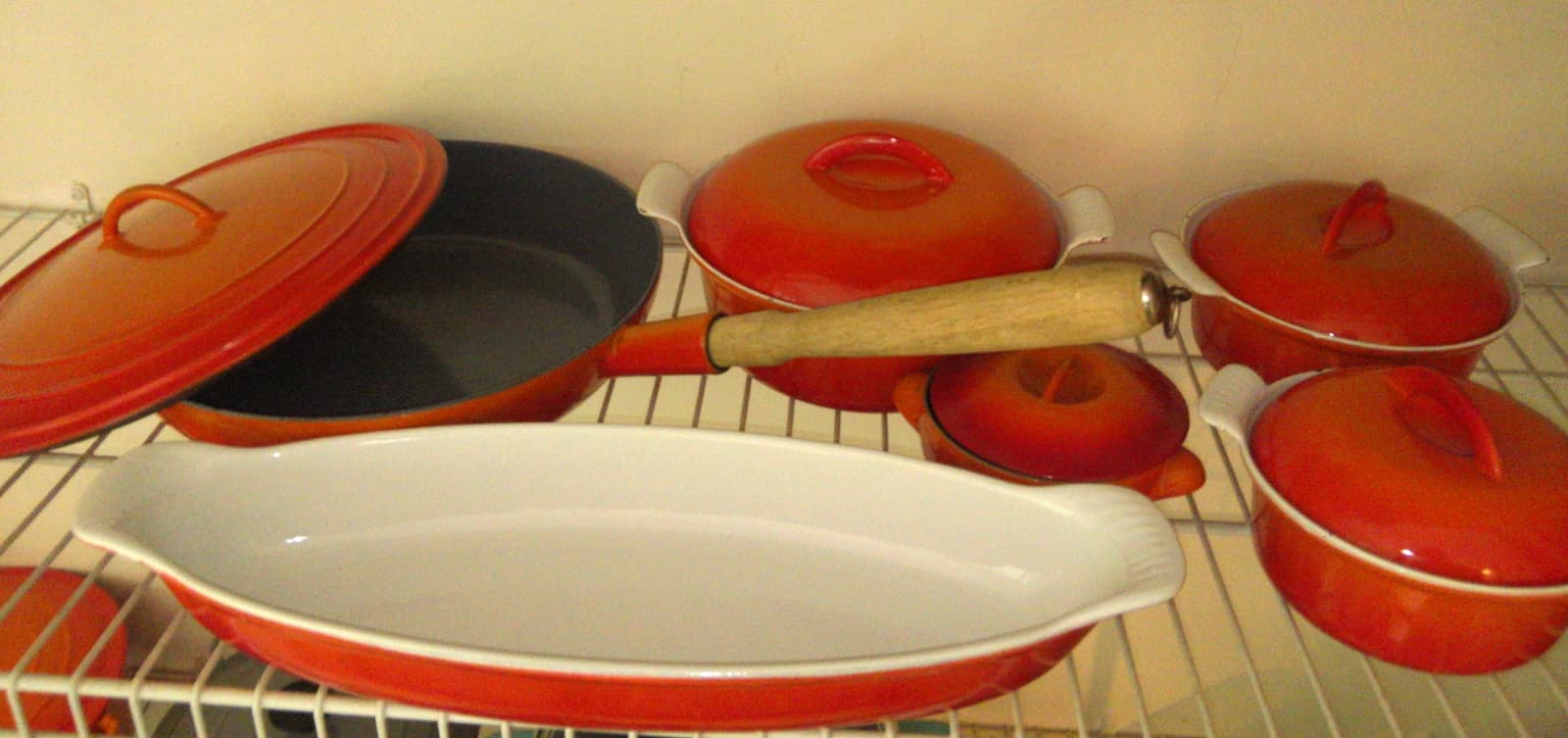 Collection of orange and white Descoware enameled cast iron cookware items.