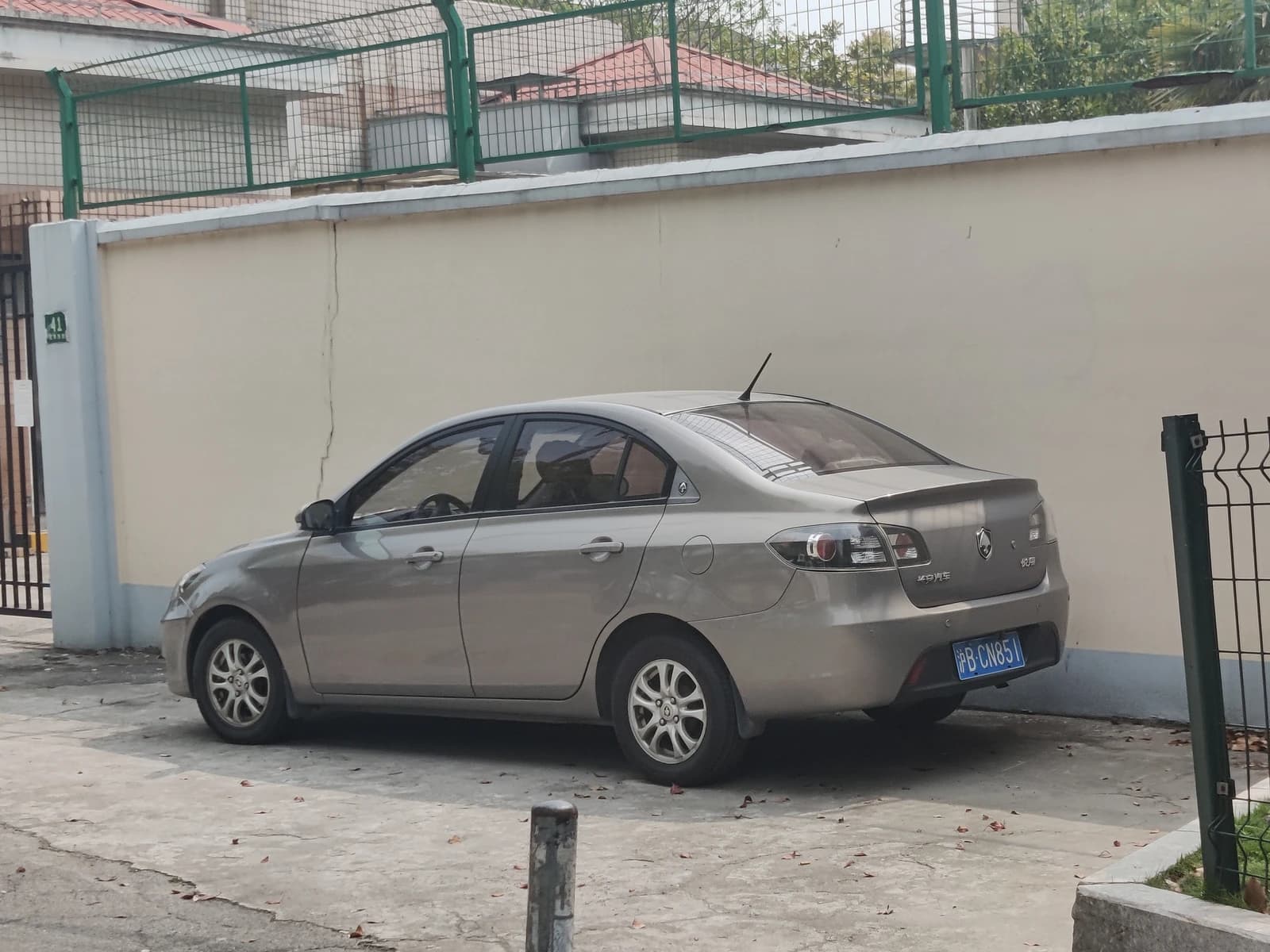 Changan Alsvin sedan in a light brown or grey color parked beside a light-colored wall.