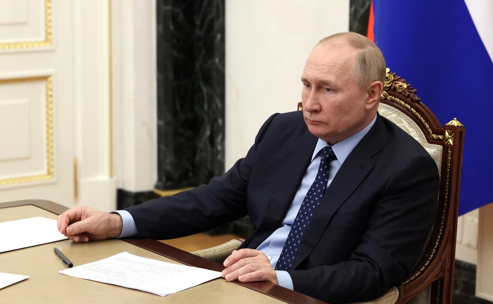 Vladimir Putin, Russian President, seated at a long table during a meeting.