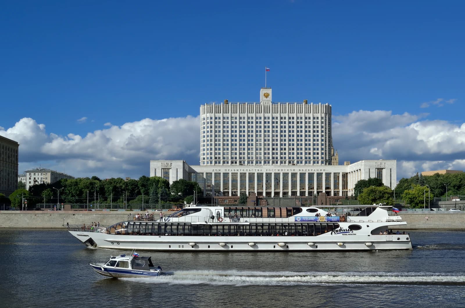 The Russian White House building with the Moskva River and two ships in the foreground.