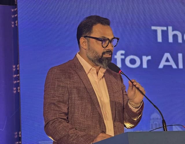 Aminul Hoque speaking into a microphone at a podium during a conference.