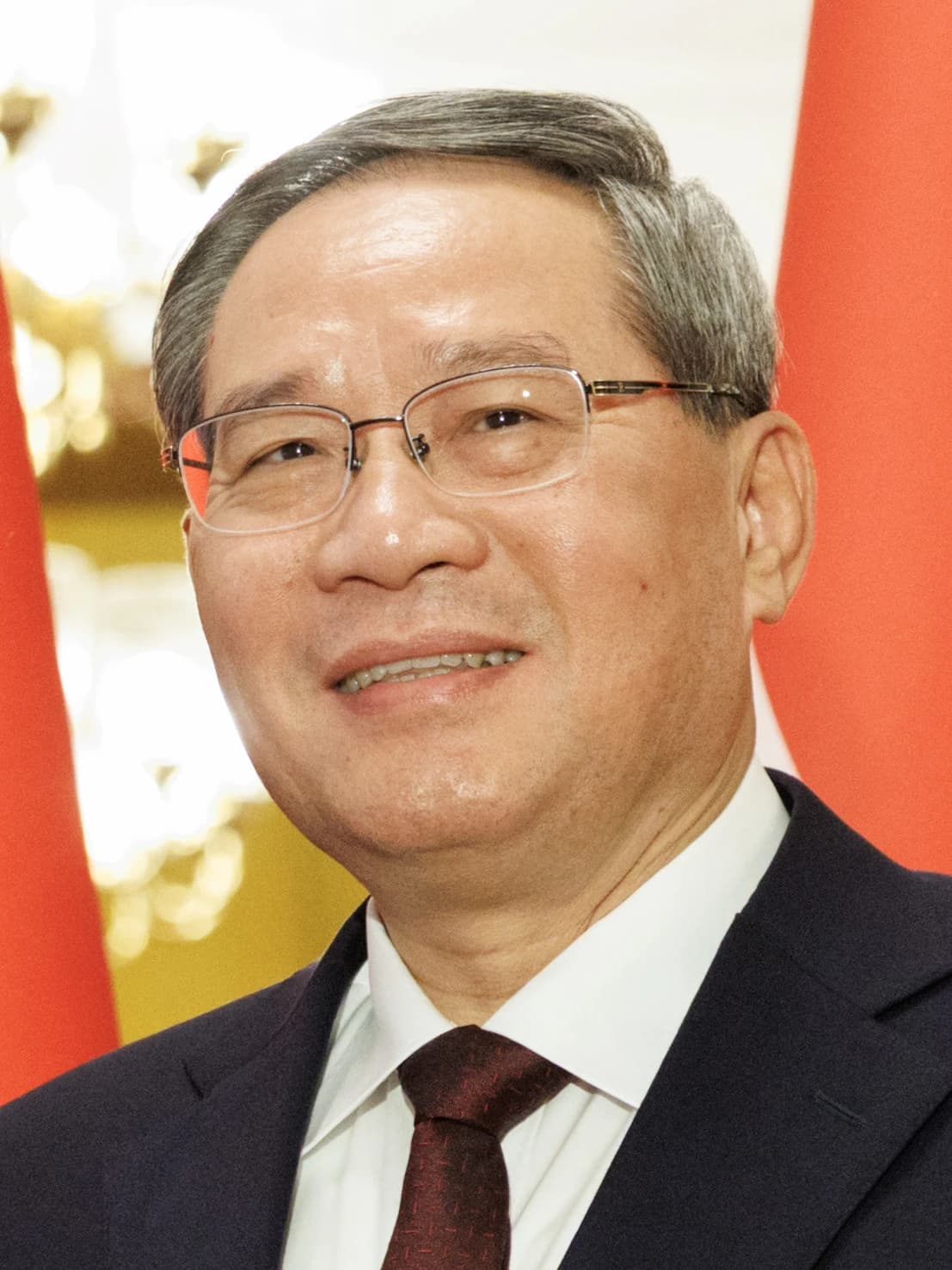 Chinese Premier Li Qiang in a suit and tie, smiling at an event.