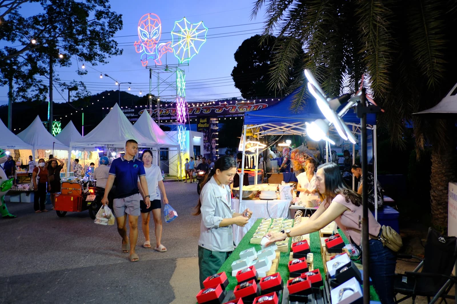 People browse goods at various stalls in a bustling evening market.