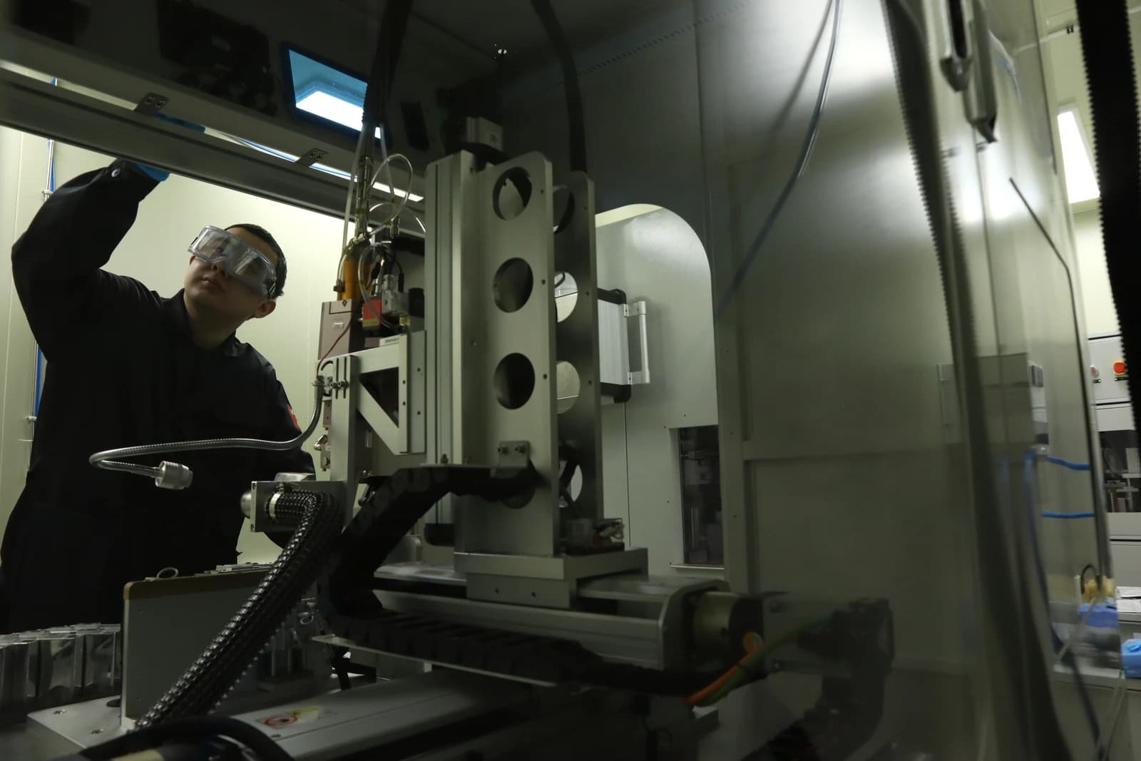 Battery researcher works with industrial-looking equipment in a laboratory setting.
