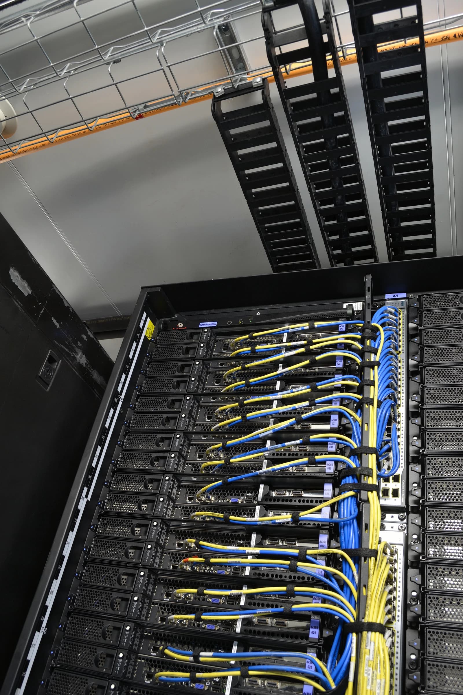 Rows of IBM blade servers with yellow and blue cables connected in a data center.