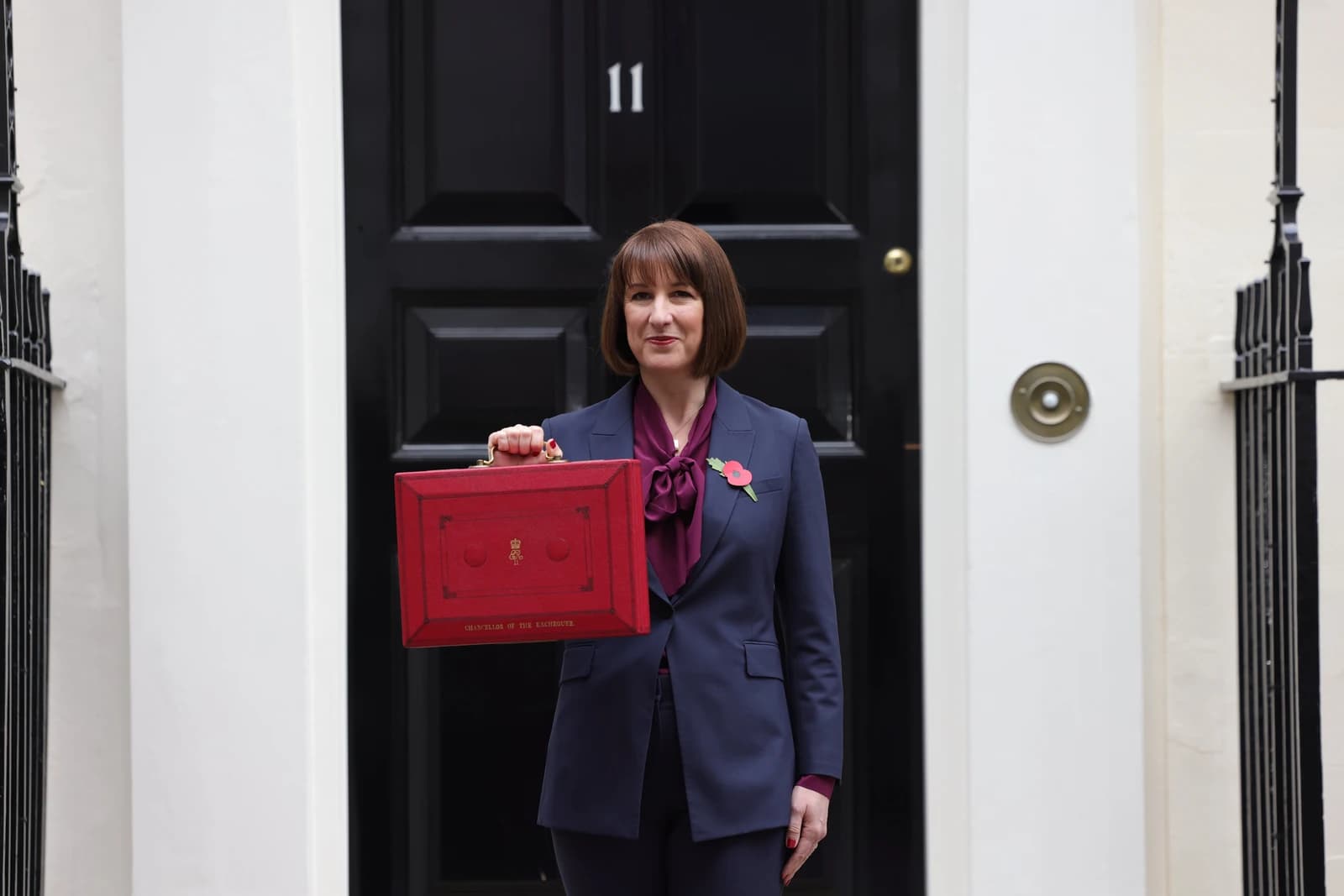 UK Chancellor of the Exchequer stands outside 11 Downing Street holding the red budget box.