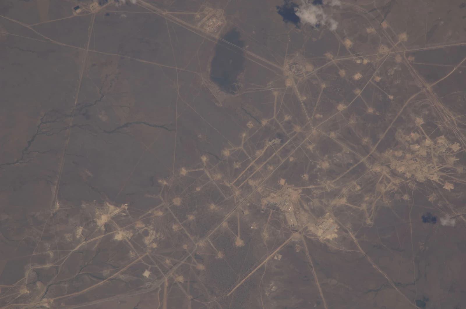 An aerial view of Kazakhstan showing vast arid land with visible oil infrastructure.