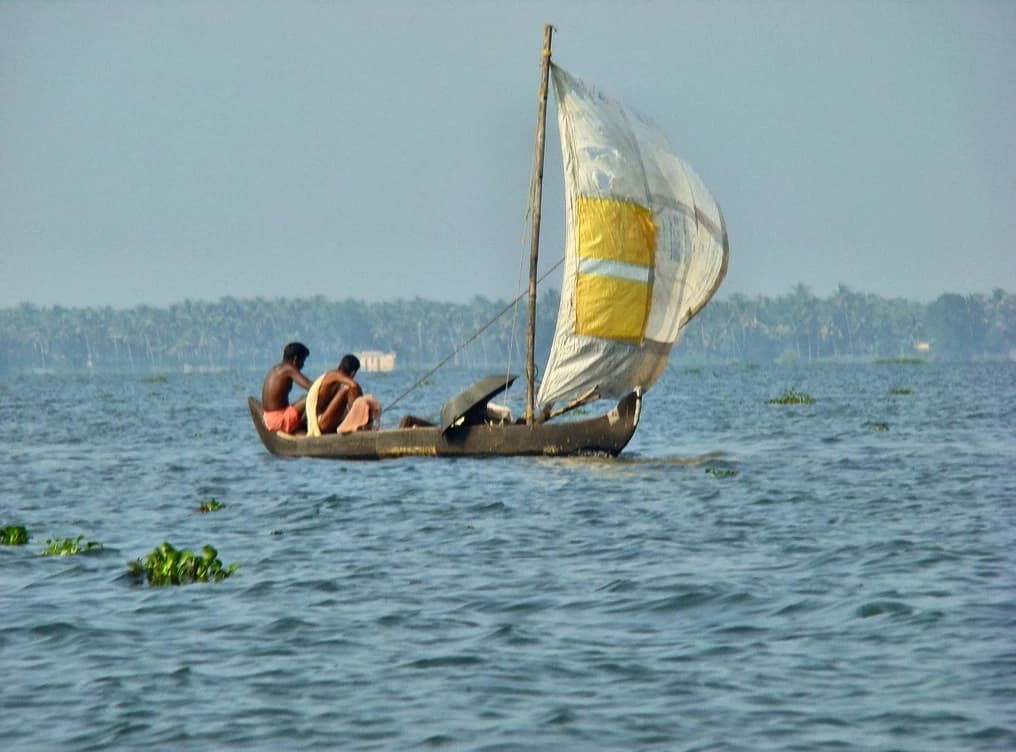 Two men on a traditional sailboat in the Kumarakom backwaters of Kerala, India.