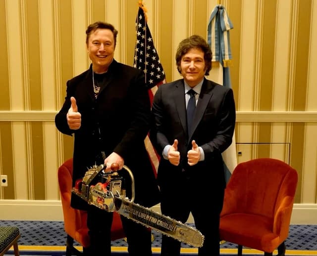 Elon Musk and Javier Milei standing, giving thumbs up, with an American flag and Argentinian flag in the background.