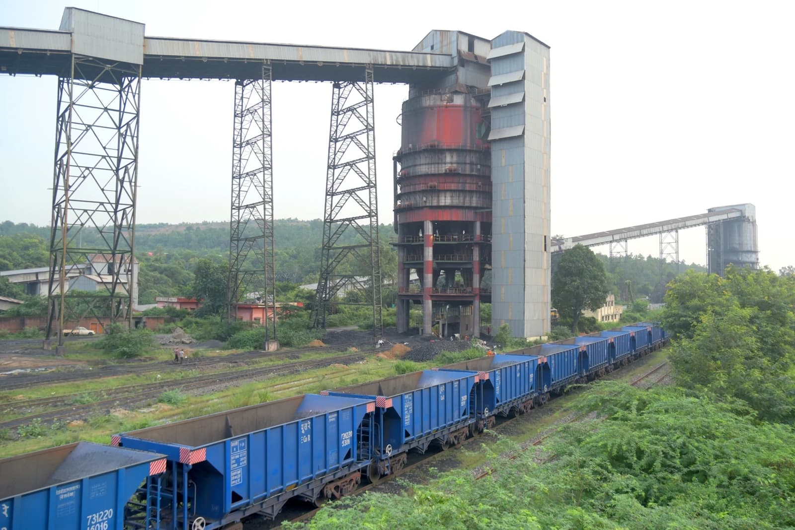 Coal handling facility with large structures and a train with blue freight cars in Singrauli.