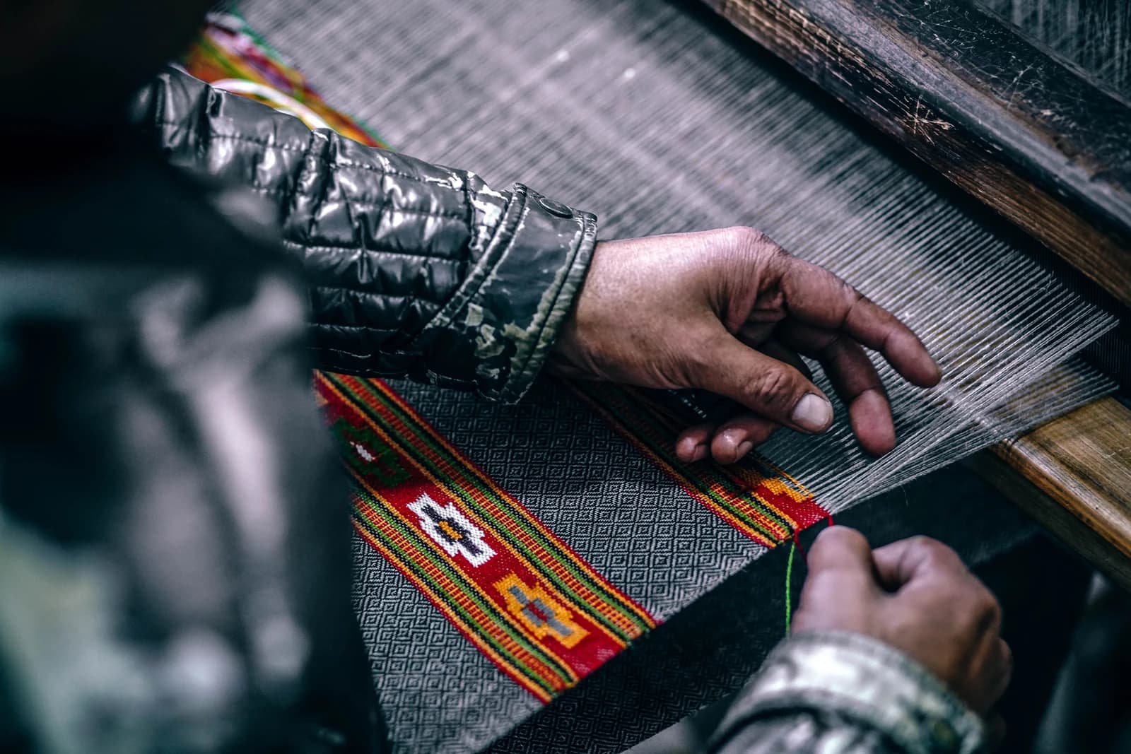 Close-up of a worker's hands operating a textile loom in a factory.