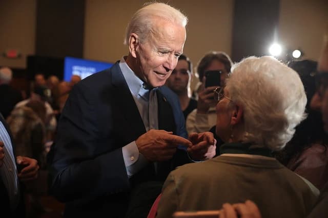 Joe Biden, then-presidential candidate, speaking with a supporter at an event.