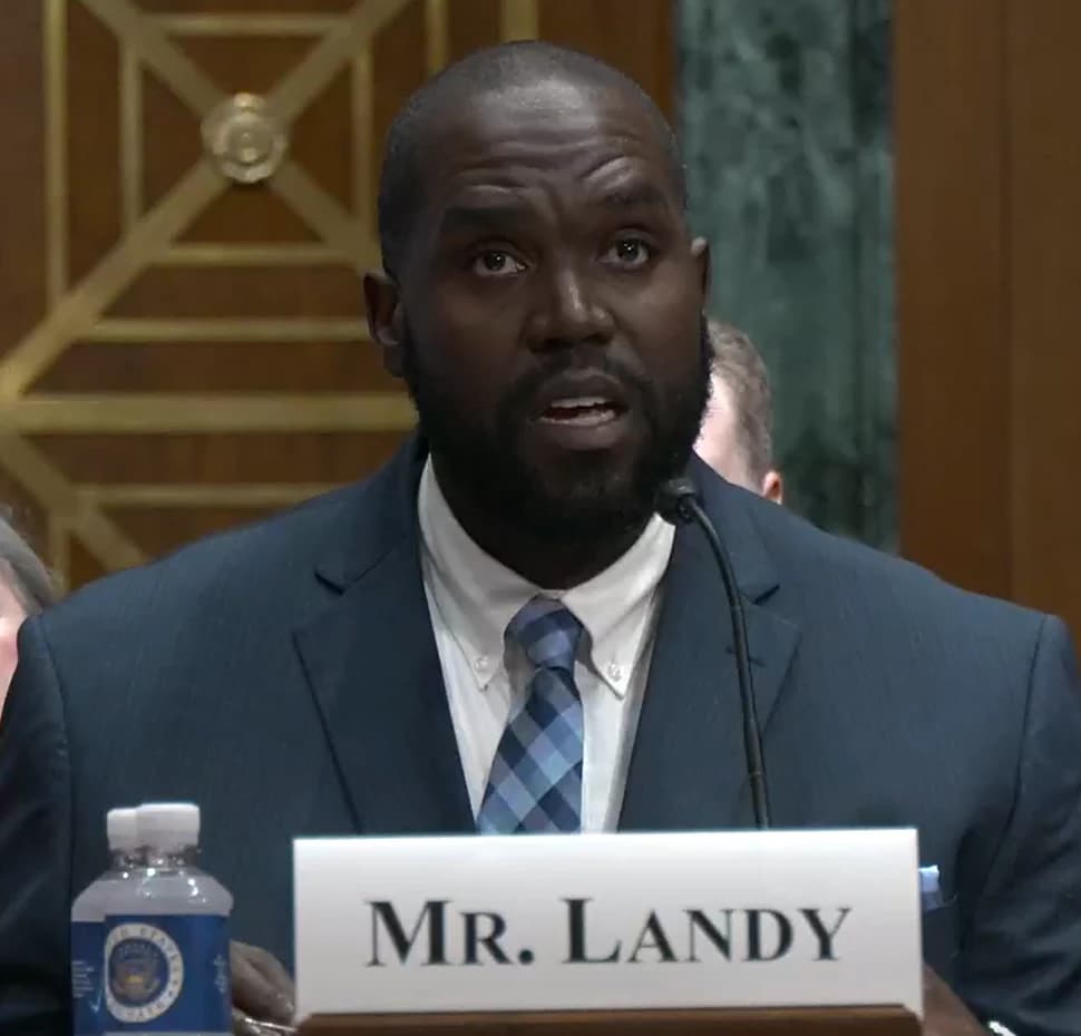 Judge Adam B. Landy speaks at a podium during a public hearing.