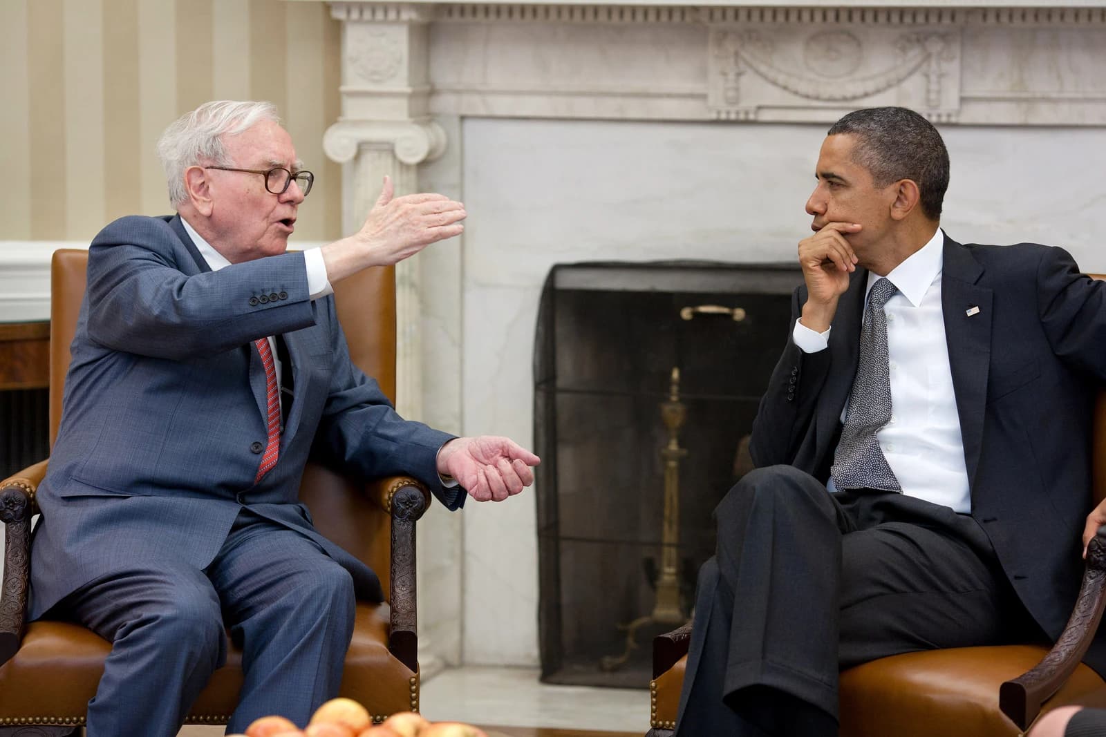 Warren Buffett, investor, speaking with Barack Obama, President, in a room.