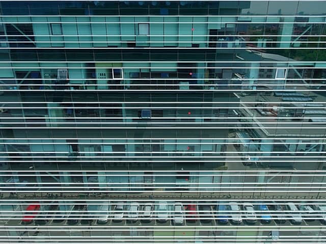 Reflective glass facade of a large corporate office building with visible interiors.