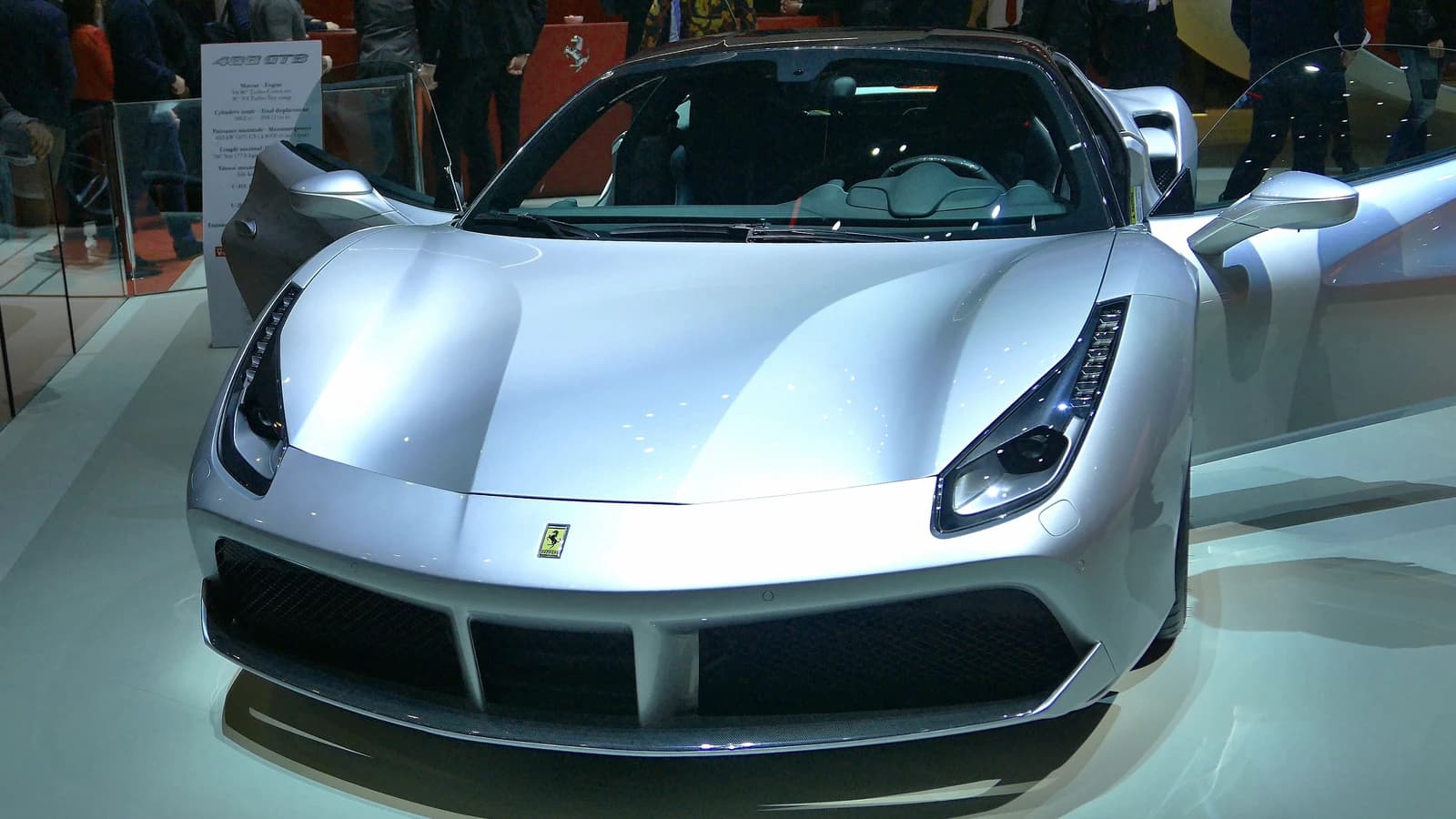 Silver Ferrari luxury sports car on display, with its doors open.