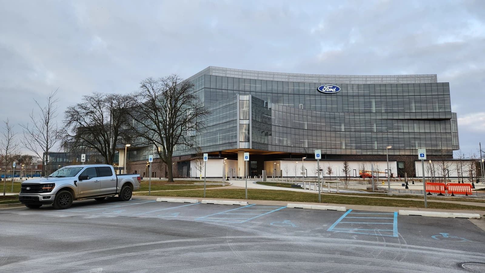 Ford World Headquarters building with a silver Ford F-150 truck in the parking lot.