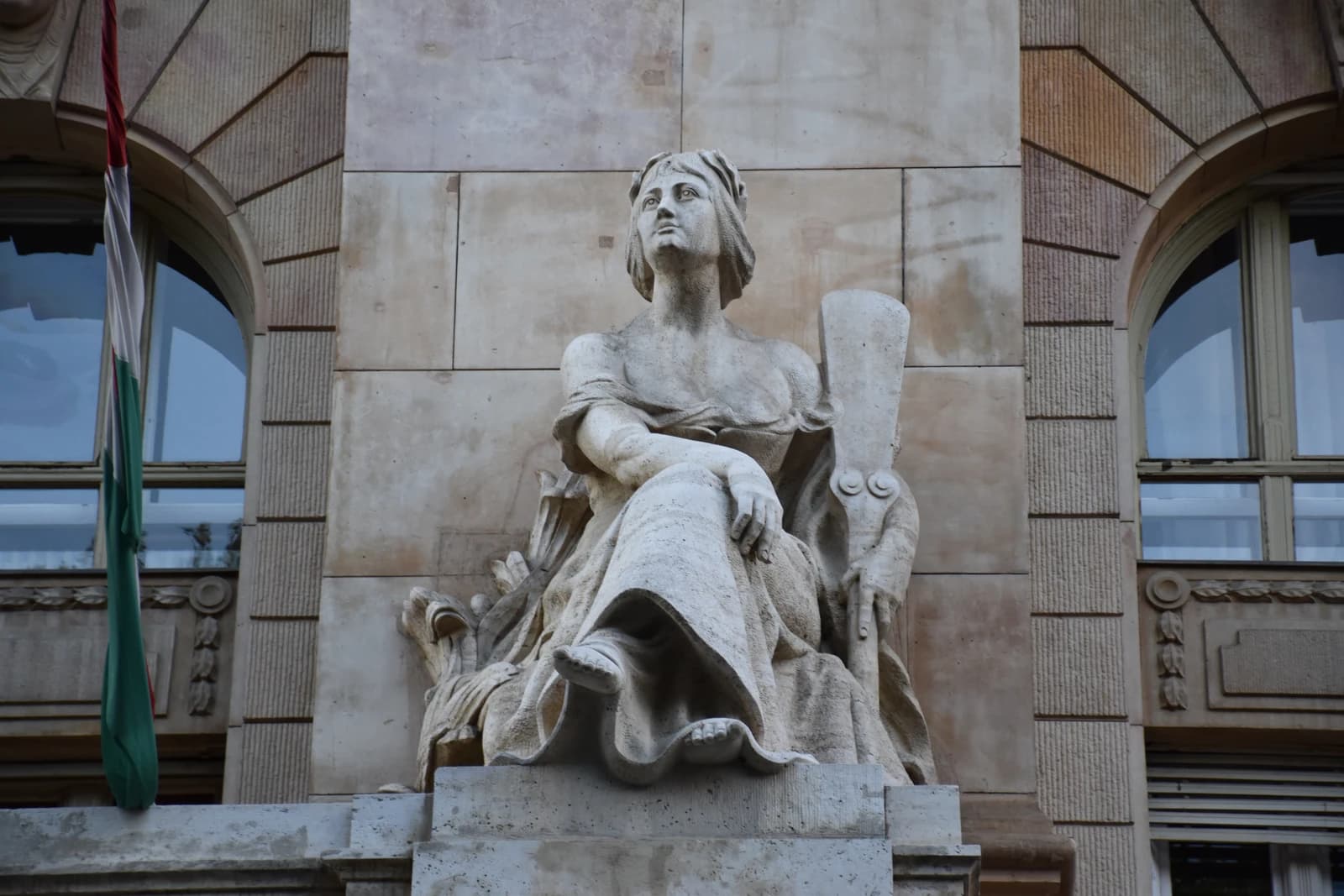 Close-up of a classical-style stone statue on the facade of the Hungarian National Bank.