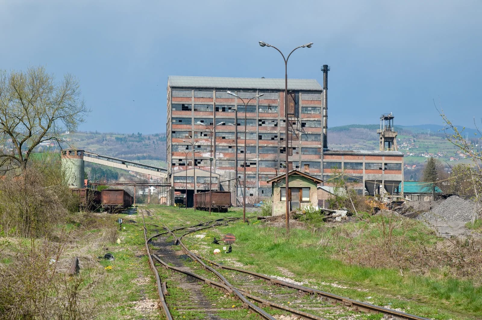 Exterior of the Breza coal mine facility with brick buildings and train tracks.