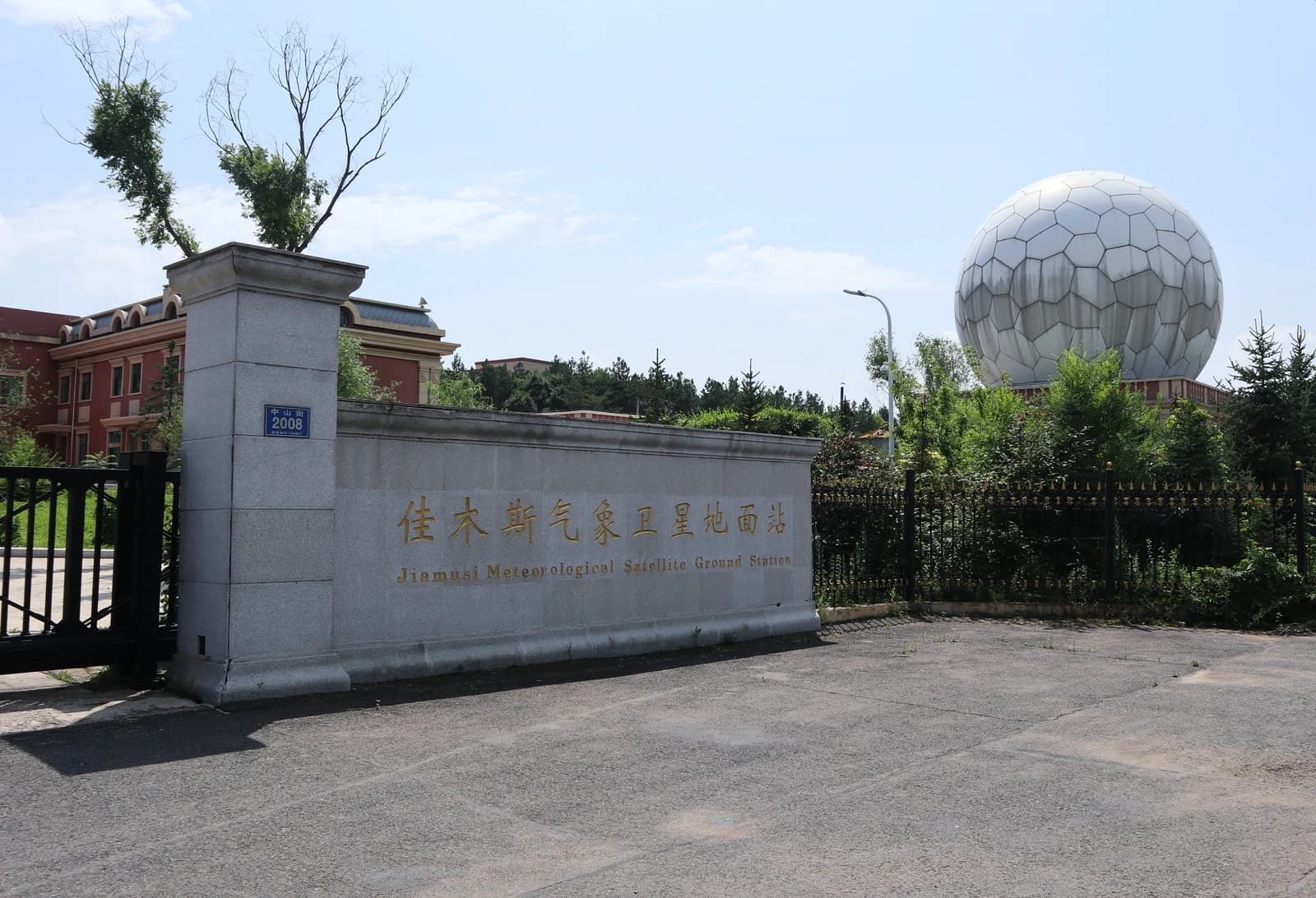 Entrance to Jiamusi Meteorological Satellite Ground Station with a large radome in the background.