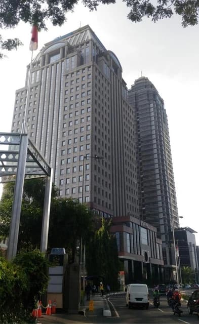 Exterior view of the Artha Graha Building and another skyscraper on a city street.