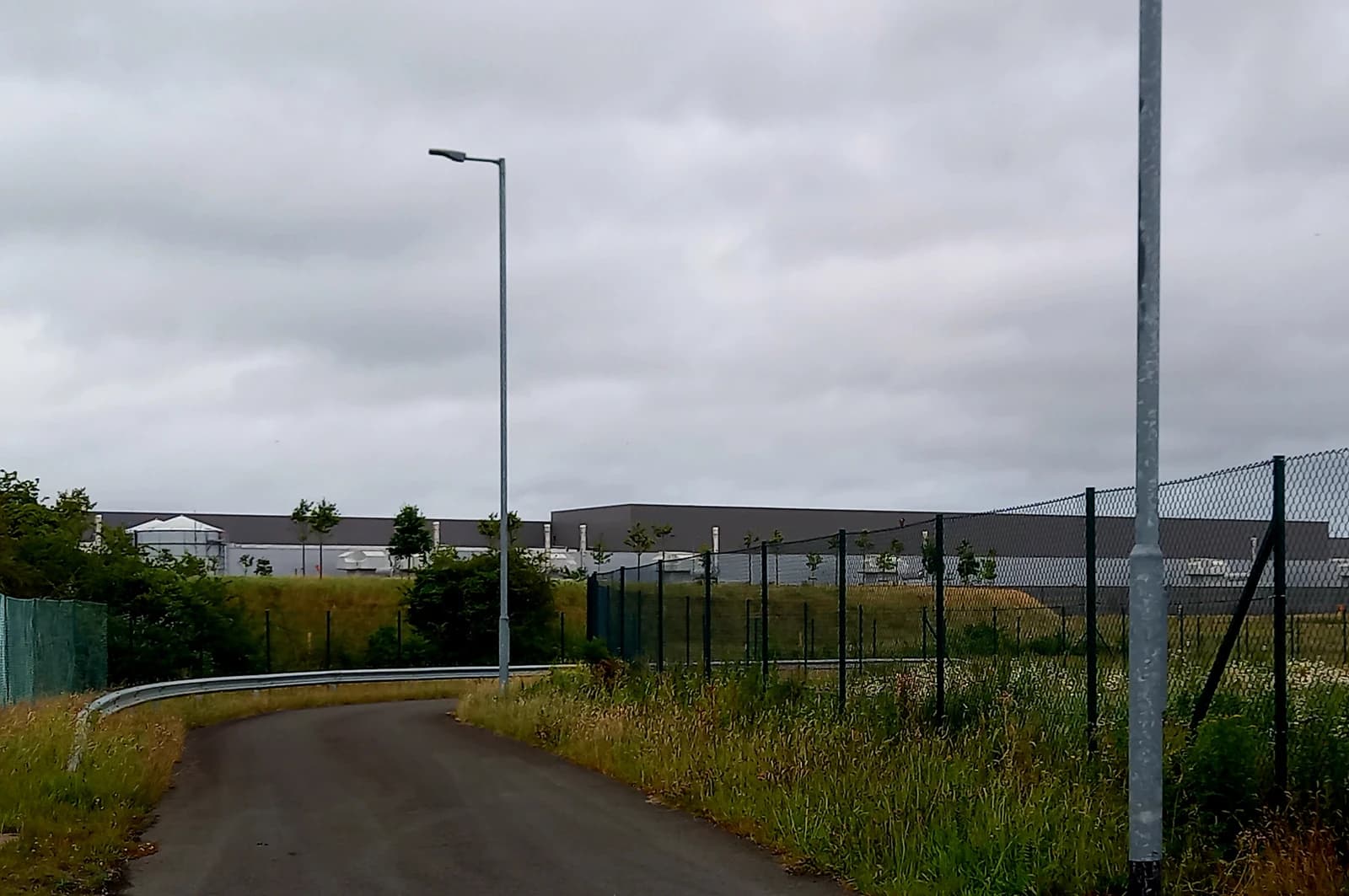 Meta head office building in Ireland, seen over a fence from a curving road.