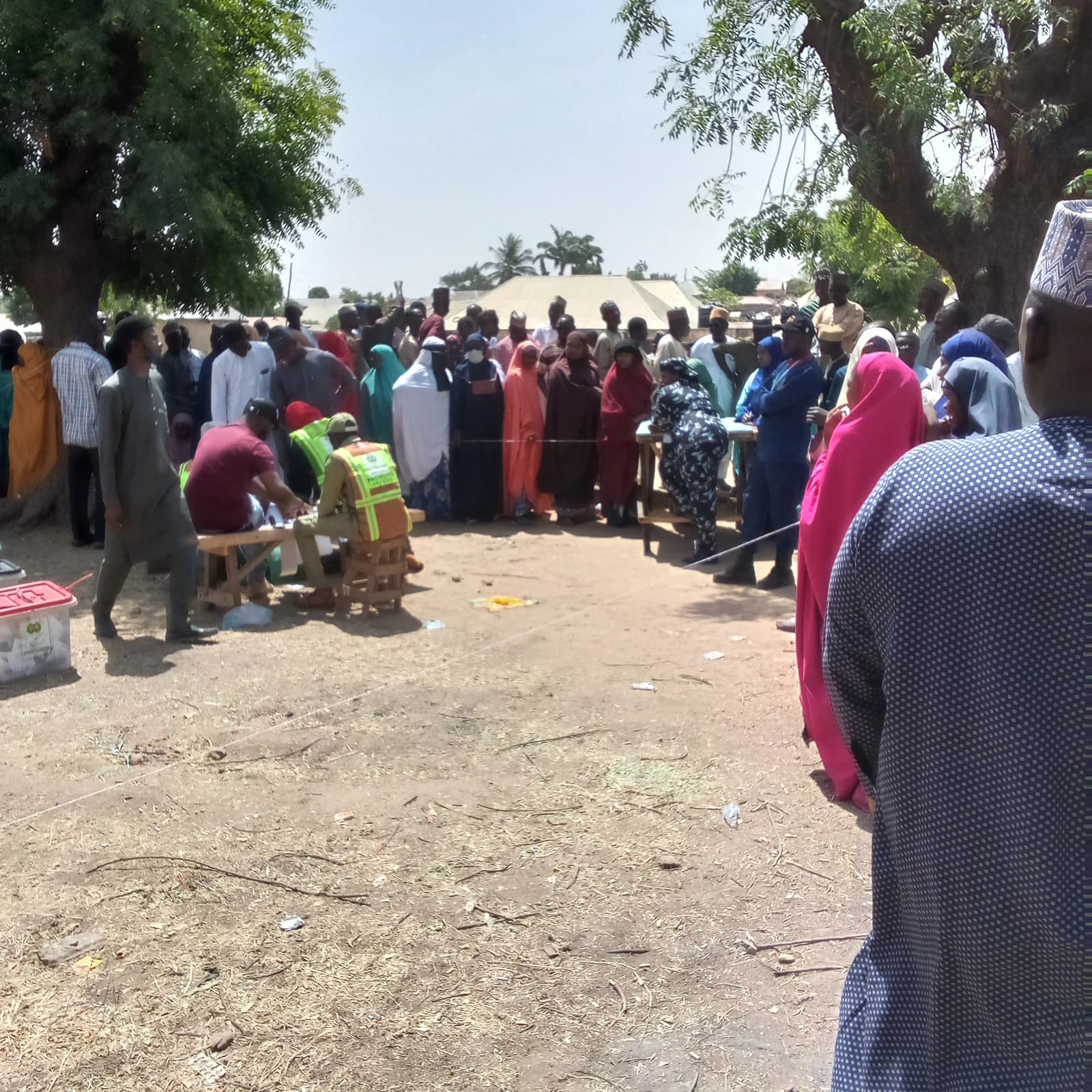 Voters in traditional attire queue at an outdoor polling station in Gombe, Nigeria.