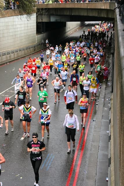 Runners in colorful sportswear crowd a city street during the London Marathon event.