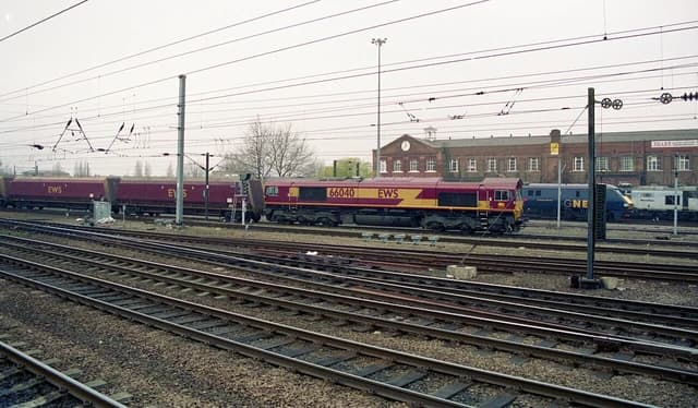 A red and yellow locomotive with '66040' and 'EWS' on its side pulls freight cars.