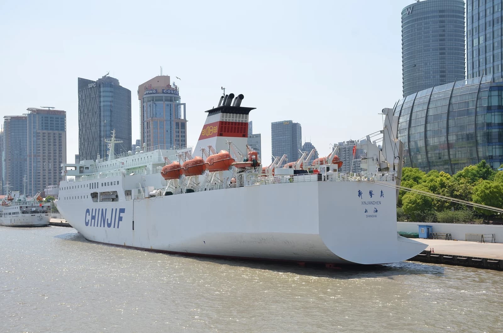 Cargo ship MV Xinjianzhen docked at the Port of Shanghai on a sunny day.