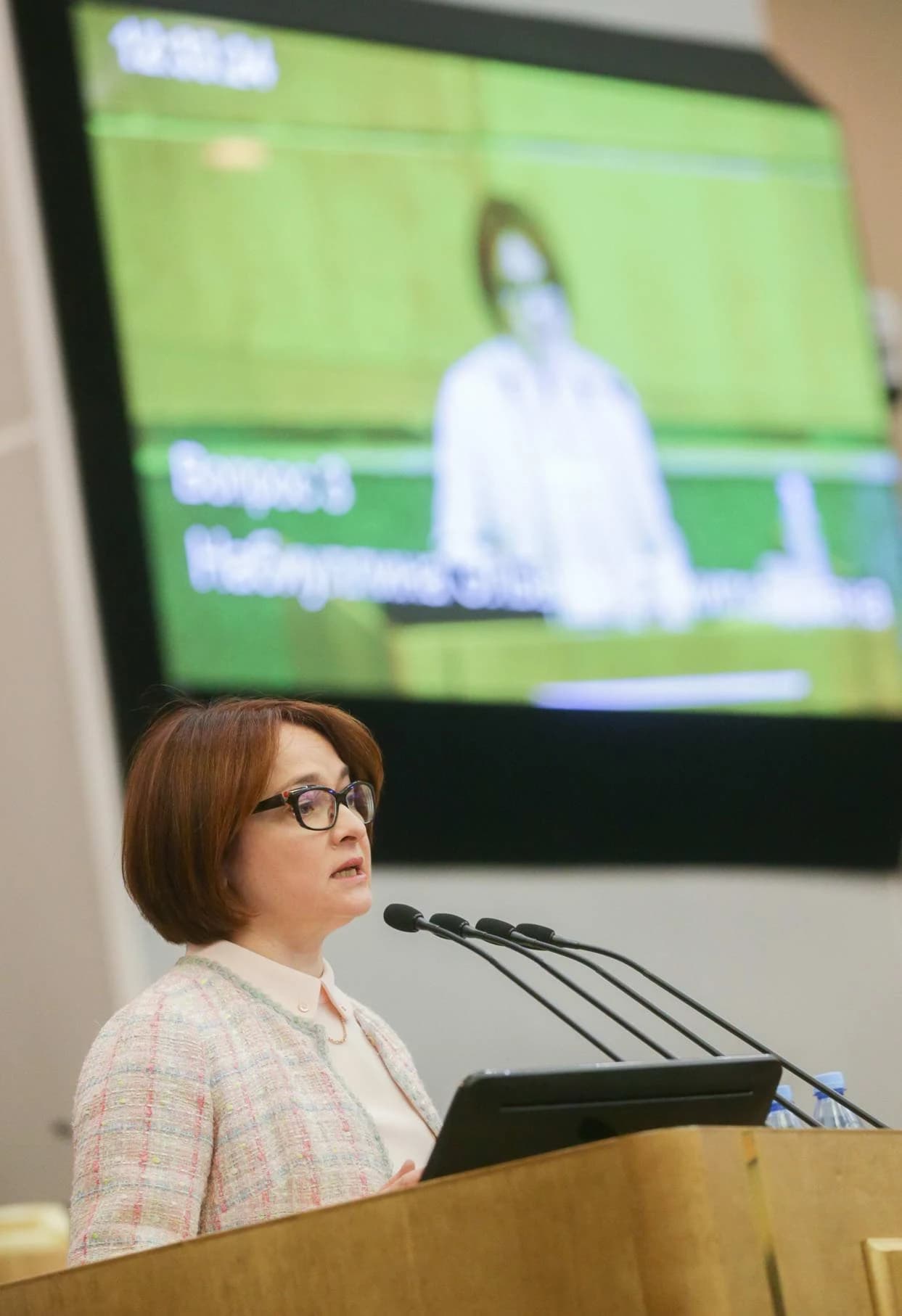 Elvira Nabiullina, Governor of the Bank of Russia, speaks at a multi-microphone podium.