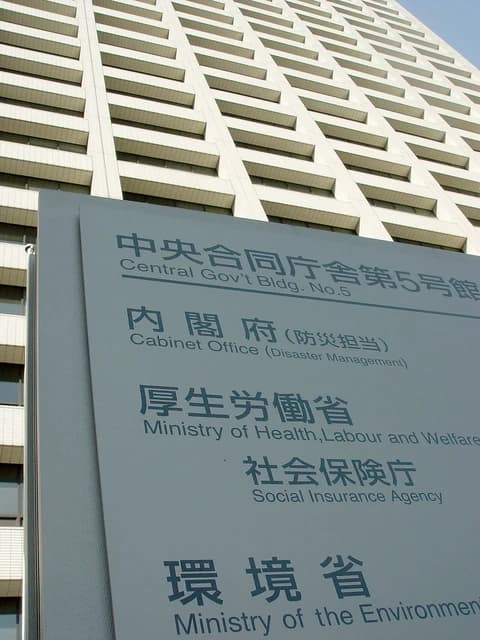 Signboard for Japan's Ministry of Health, Labour and Welfare, with building in background.