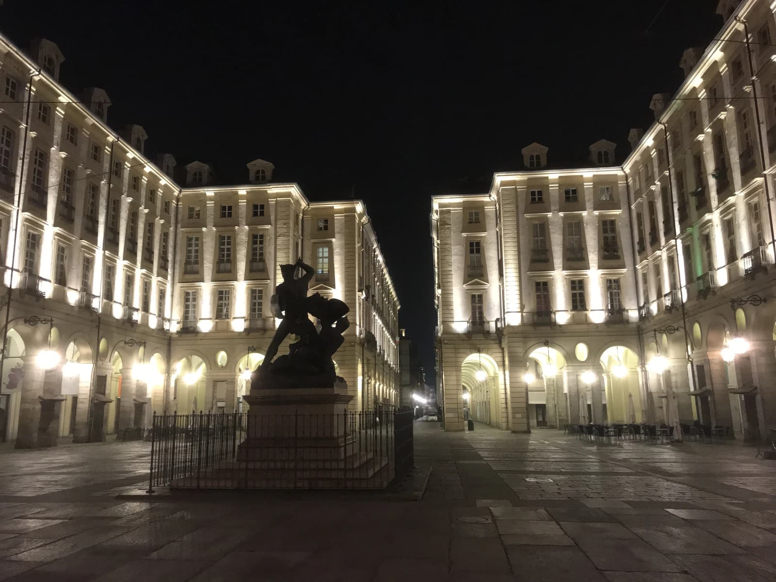 Night view of Piazza Palazzo di Citta, Turin, with illuminated buildings and a statue.