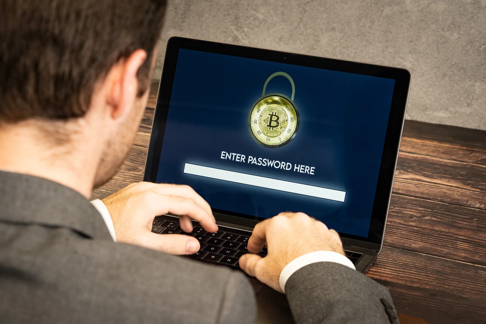 Man typing on a laptop computer with Bitcoin padlock on screen.