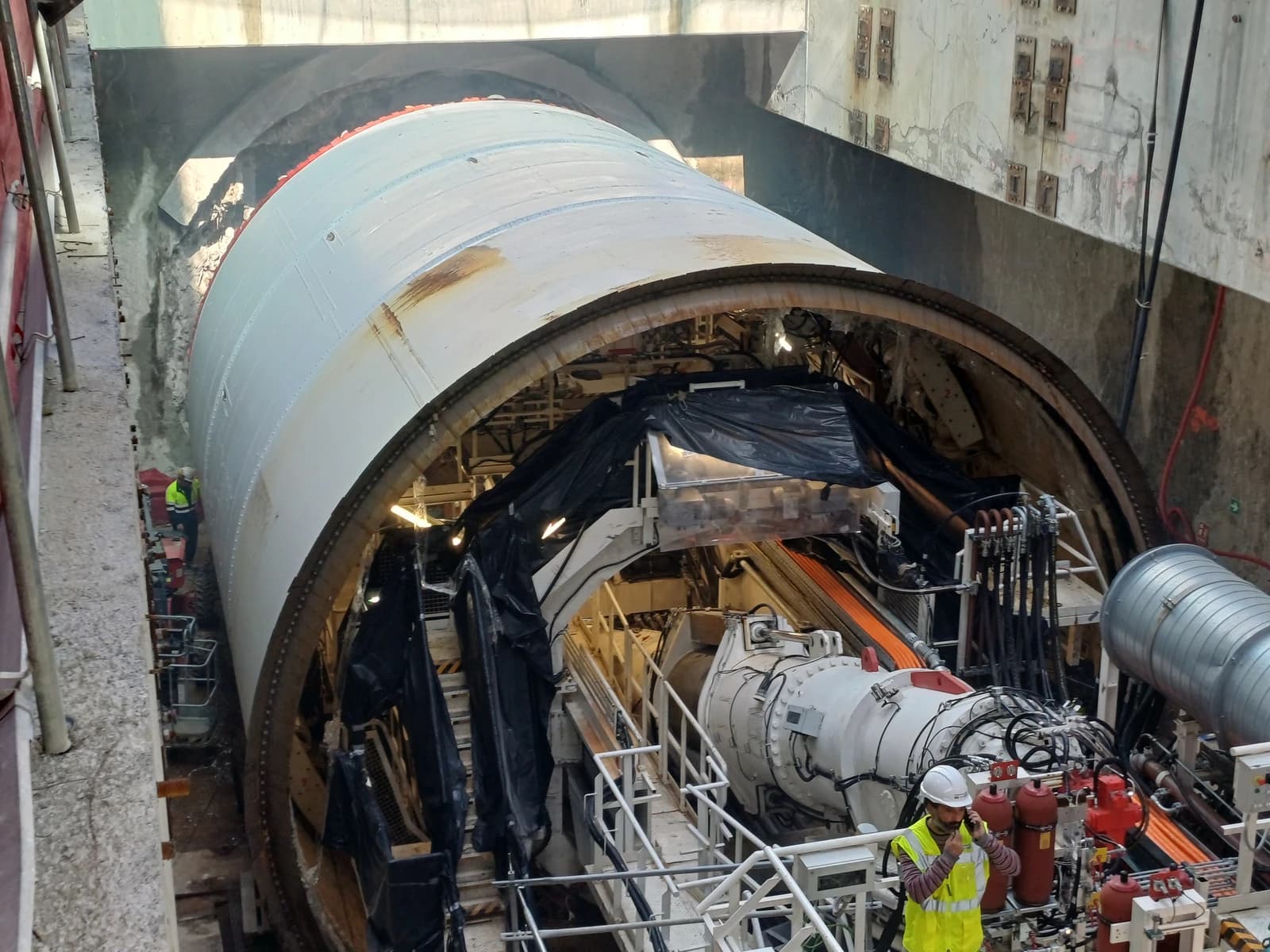 A large tunnel boring machine at a construction site with workers nearby.