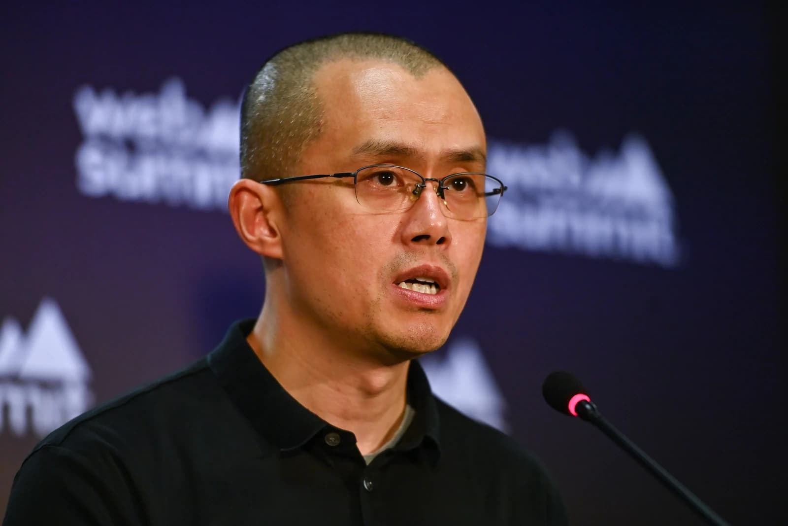 Changpeng Zhao, CEO of Binance, speaks into a microphone at a press conference.