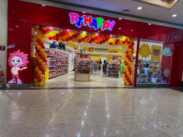 Exterior of a brightly lit Ri Happy toy store in a shopping mall.