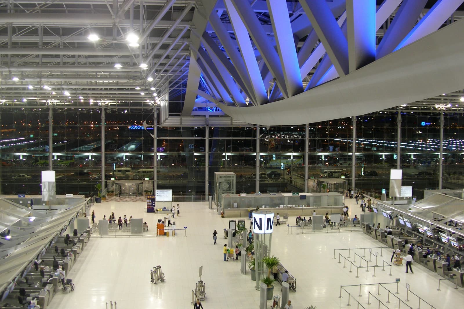 People walk and wait in the expansive main hall of Suvarnabhumi Airport, Bangkok.