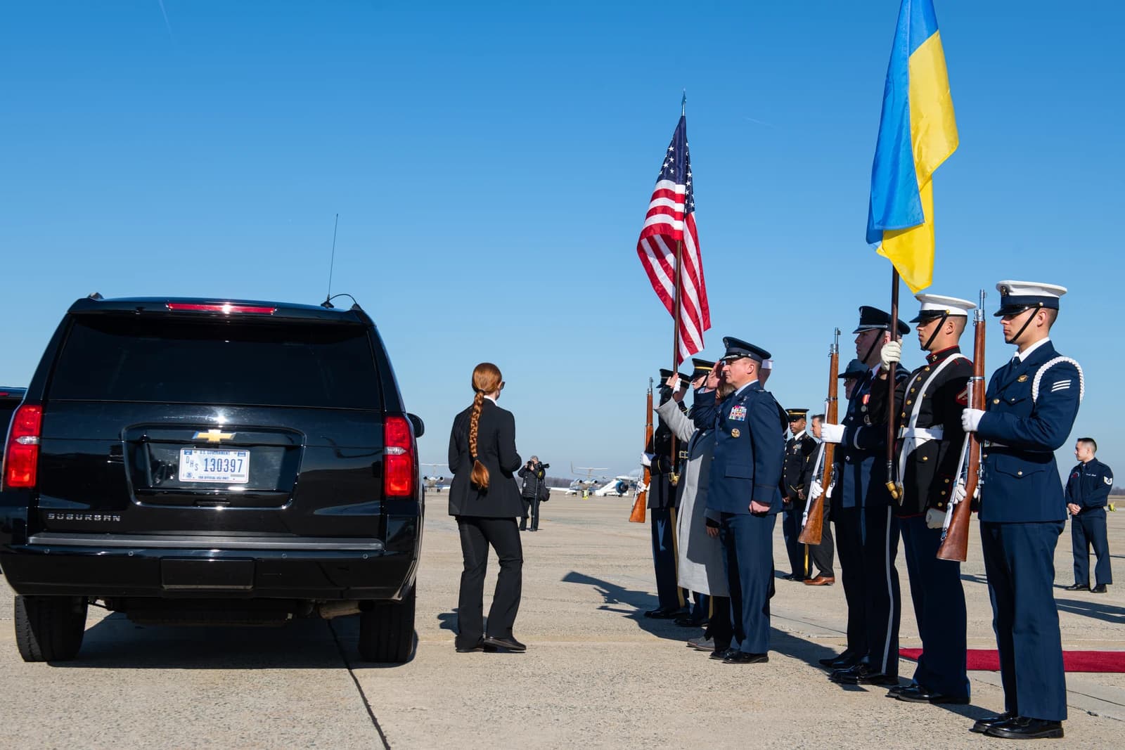 Military personnel in uniform stand in formation with US and Ukrainian flags.