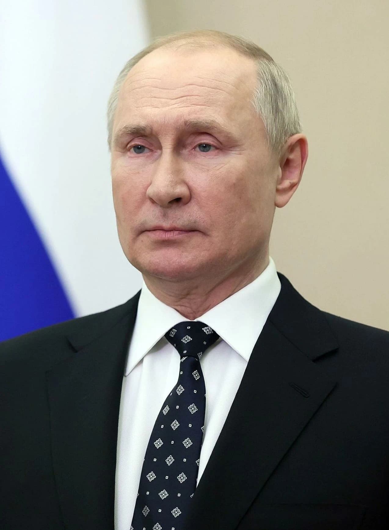 Vladimir Putin, President of Russia, stands in a formal setting.