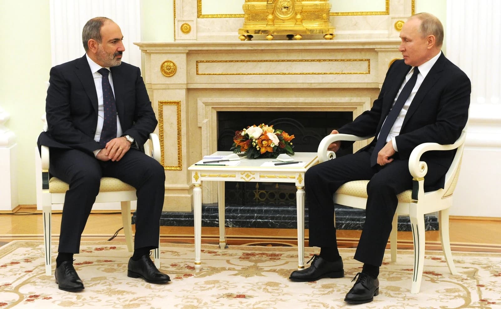 Russian President Vladimir Putin and Armenian Prime Minister Nikol Pashinyan sit across from each other.