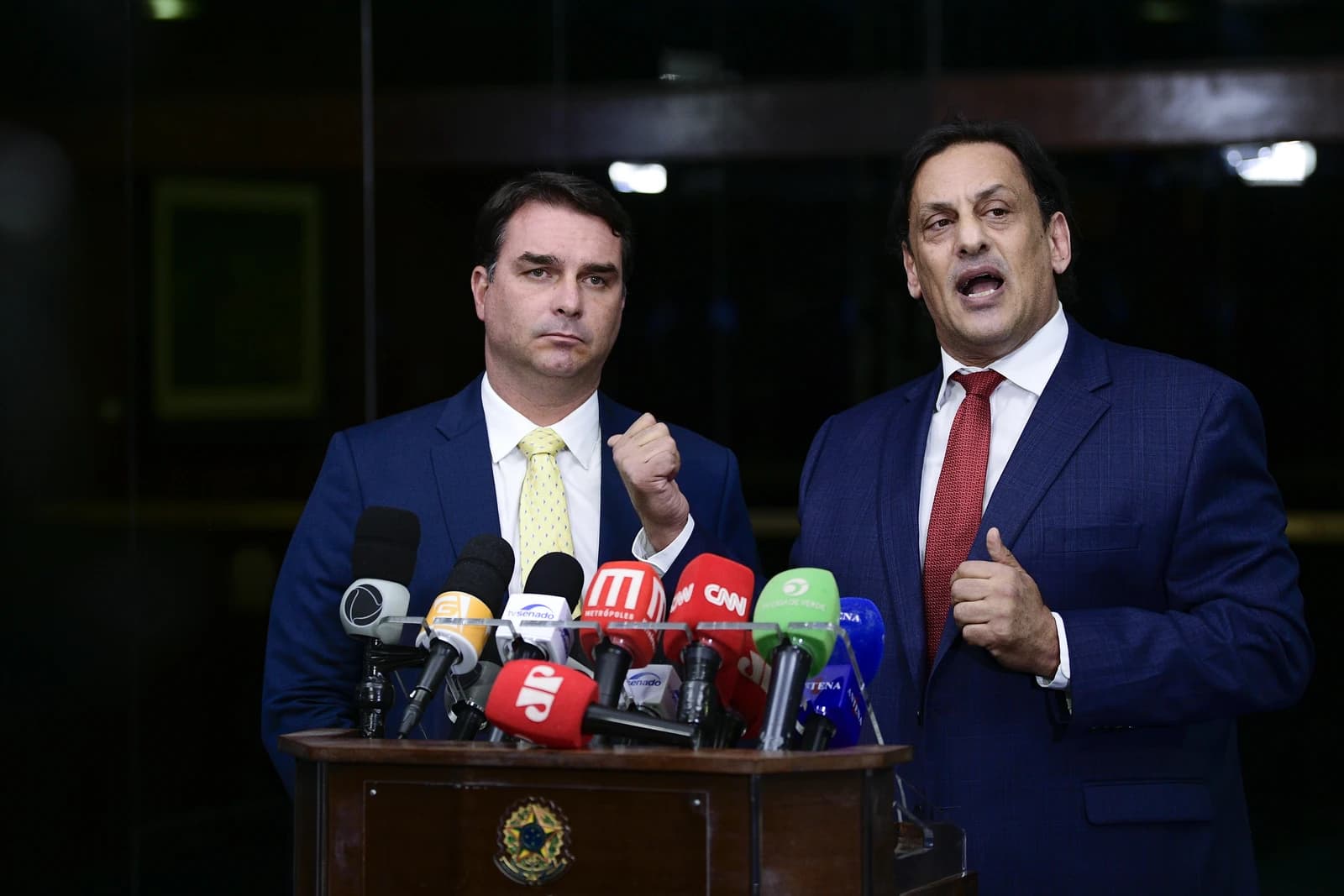 Flávio Bolsonaro, Brazilian senator, and Frederick Wassef, lawyer, at a podium with microphones.