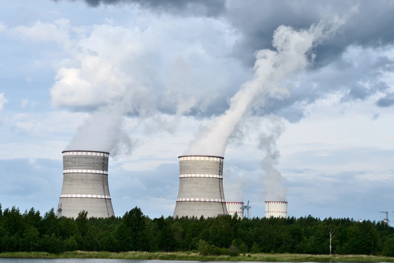Multiple cooling towers of a nuclear power plant emitting large plumes of steam.